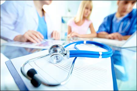 Stethoscope And Document On Background Of Doctors And Patient Working With Laptop