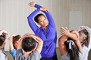 PE teacher shows her class how to stretch