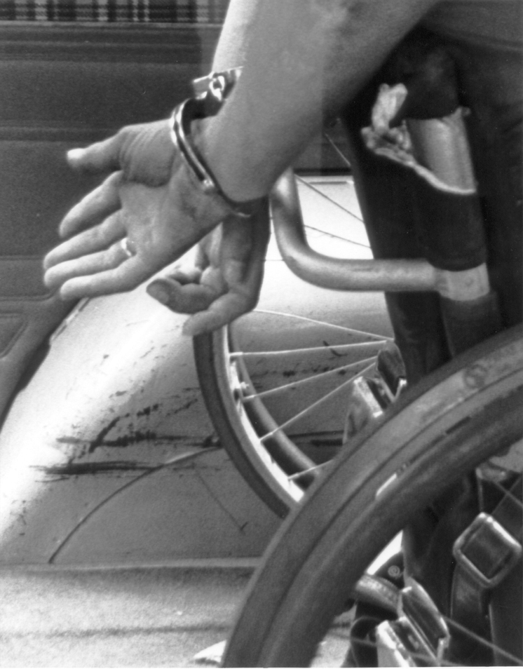 Hands cuffed behind wheelchair
