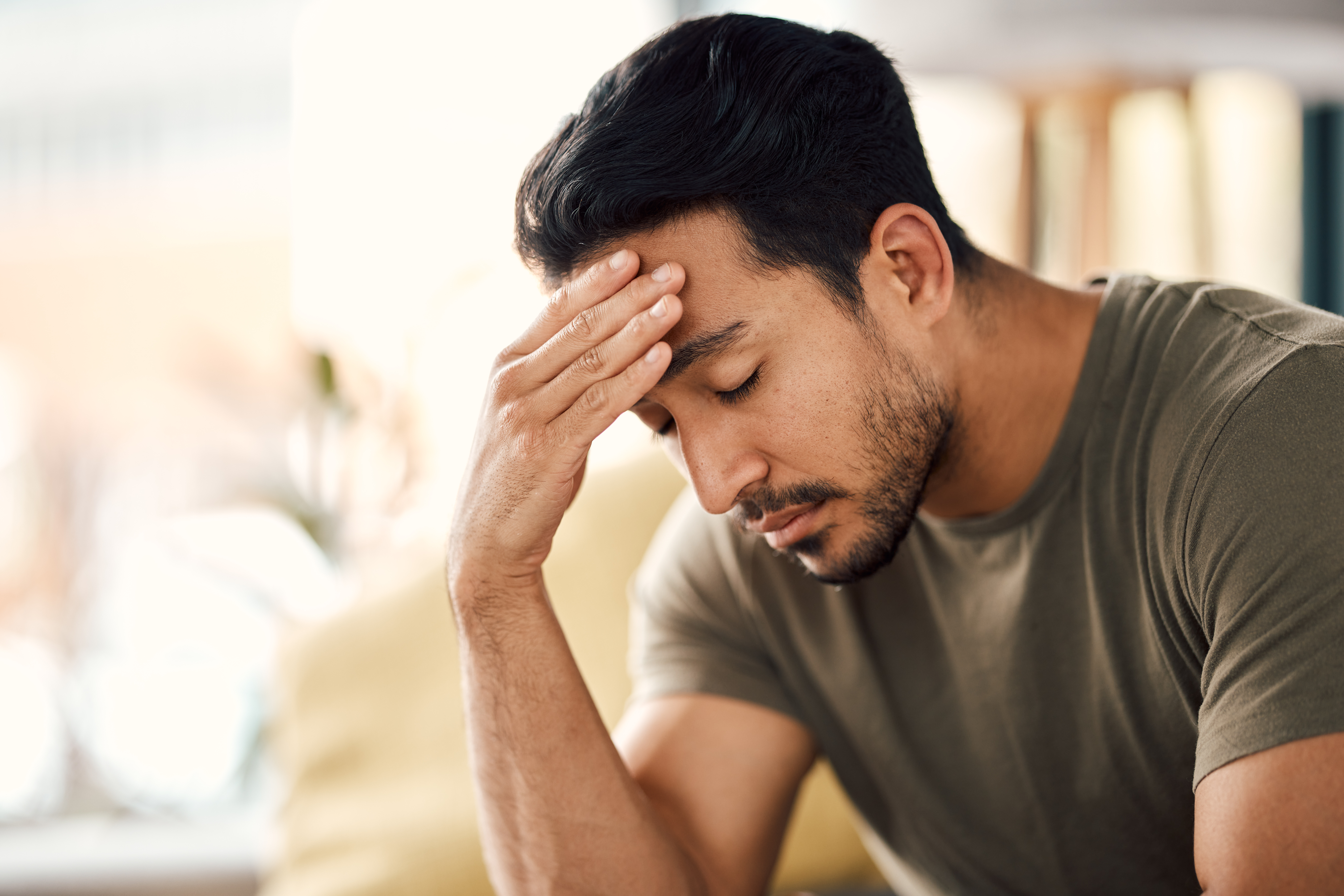 A man slouching with a hand rubbing his forehead