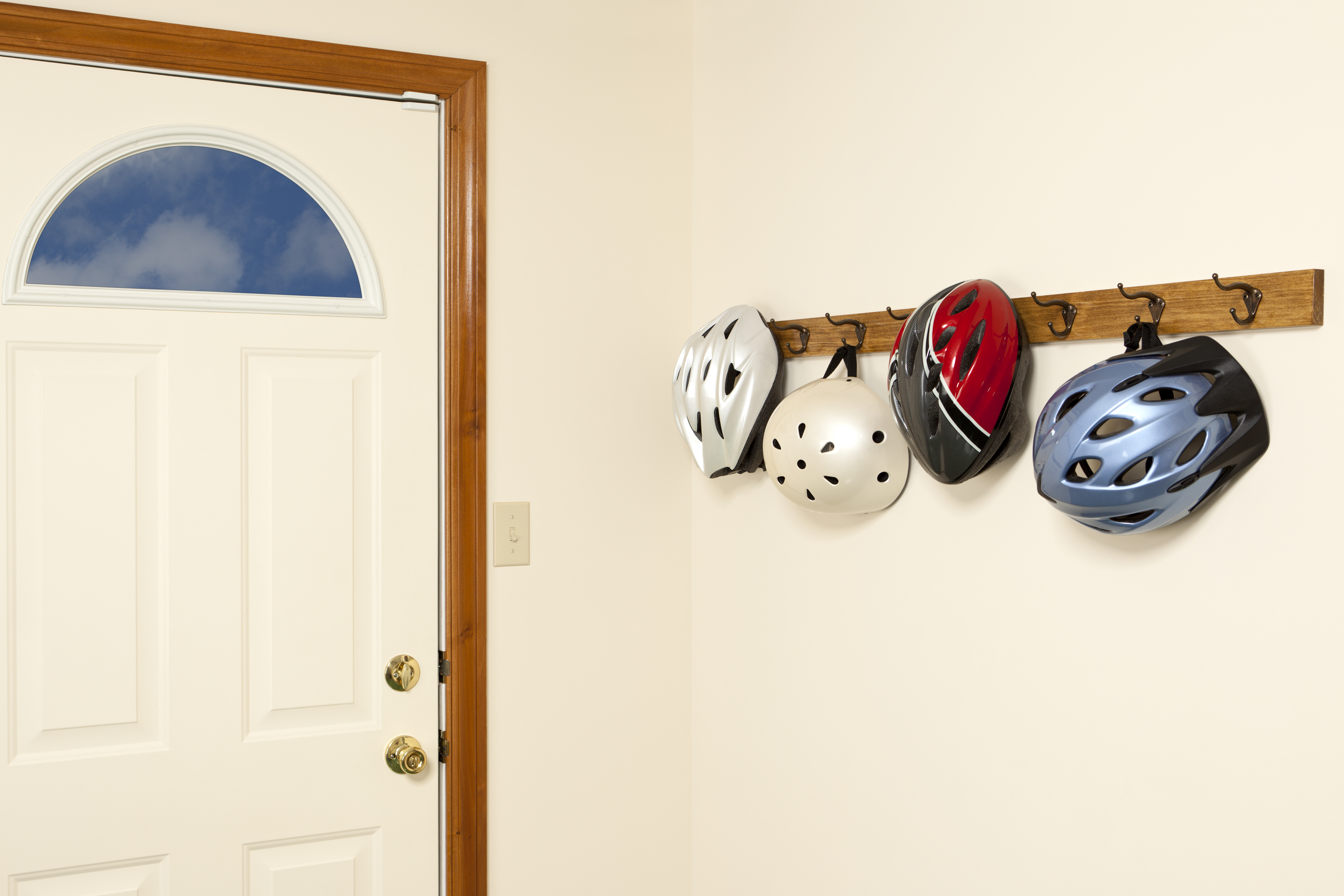 An entry way to a home with four bicycle helmets hanging on hooks